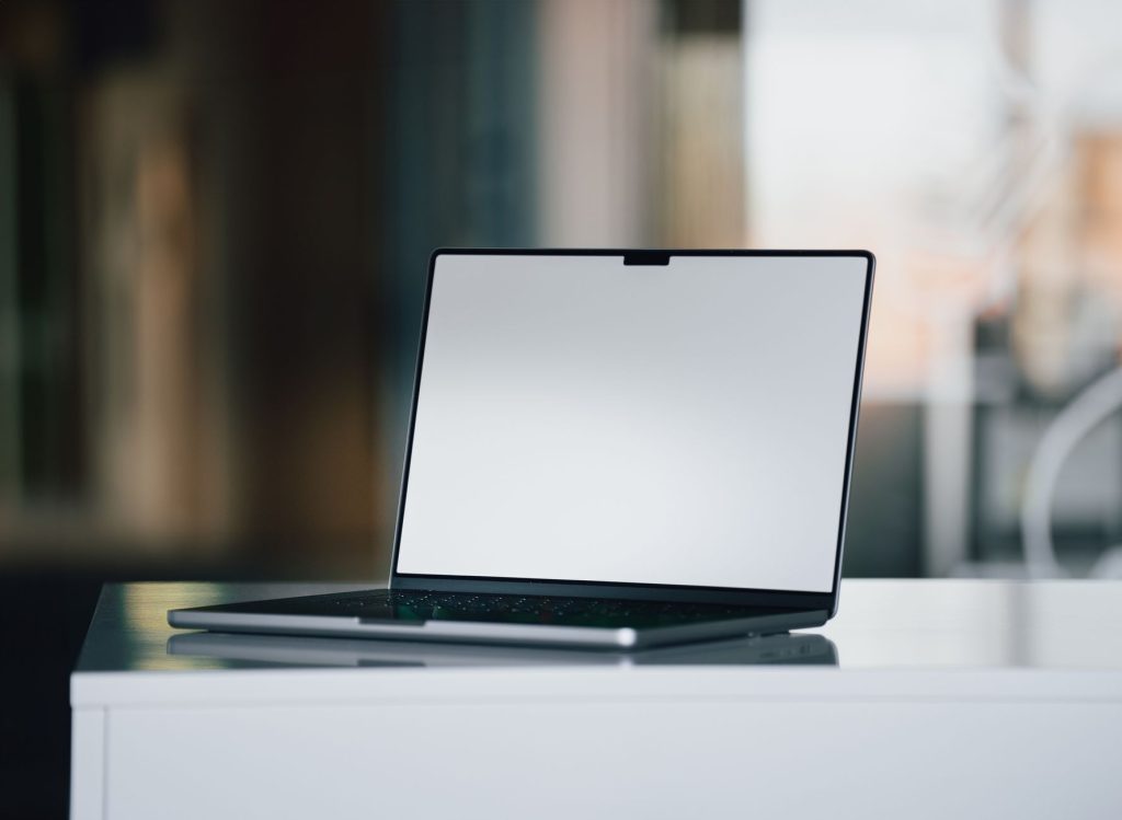 Notebook elegante com tela apagada sobre uma mesa branca em um escritório contemporâneo